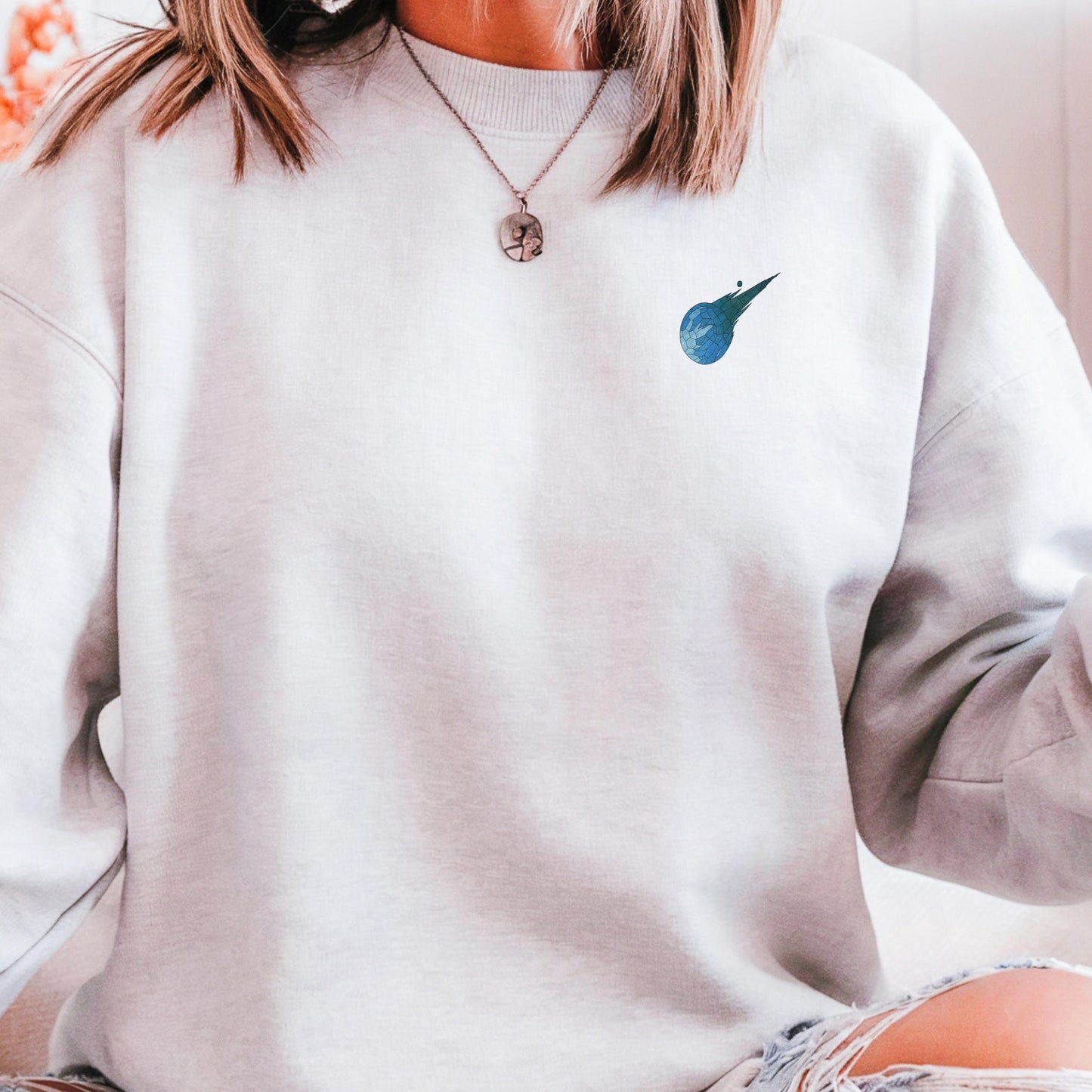 Stained glass style Final Fantasy meteor logo on a white sweater.