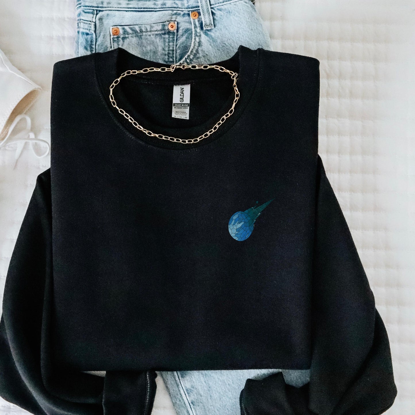 Stained glass style Final Fantasy meteor logo on a black sweater, folded lay.