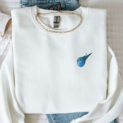 Stained glass style Final Fantasy meteor logo on a white sweater, folded lay.